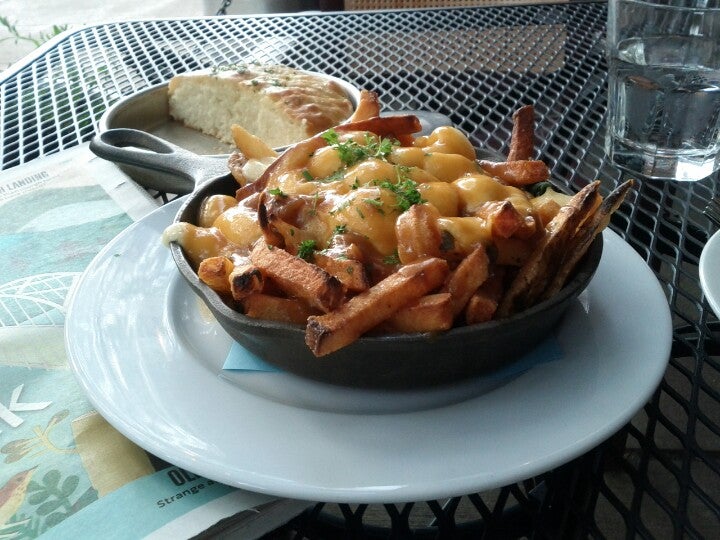 fries with cheese curds and gravy in a small iron skillet on a restaurant table with water and bread